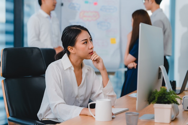 Free Photo millennial young chinese businesswoman working stress out with project research problem on computer desktop in meeting room at small modern office. asia people occupational burnout syndrome concept.