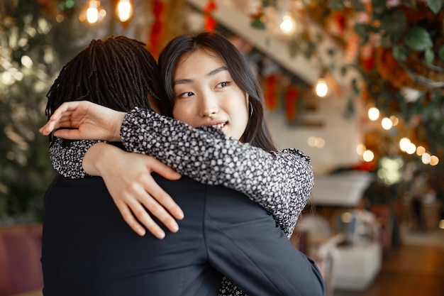 Free photo mixed couple celebrating their engagement in a cafe and hugging tightly