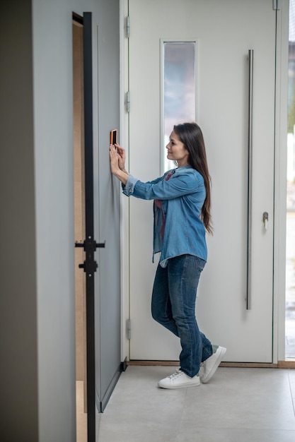 Free photo modern technologies young adult woman standing sideways to camera near smart home device