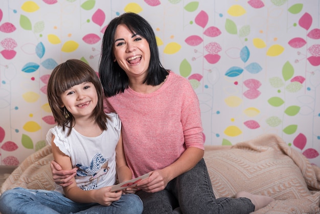 Free photo mother and daughter with greeting card smiling