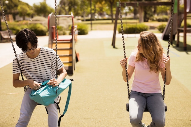 Free photo multiethnic teenagers sitting on swings