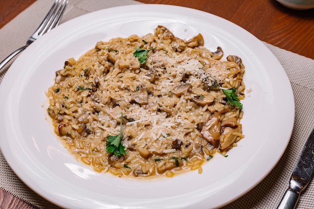 Foto gratuita risotto ai funghi guarnito con parmigiano grattugiato e prezzemolo