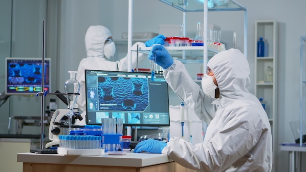 Free Photo neurologist with ppe suit working at vaccine development in equipped laboratory typing on pc. team examining virus evolution using high tech for research in treatment development against covid19