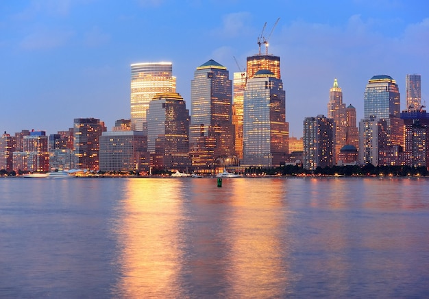 New York City Manhattan downtown skyline at dusk with skyscrapers illuminated over Hudson River panorama