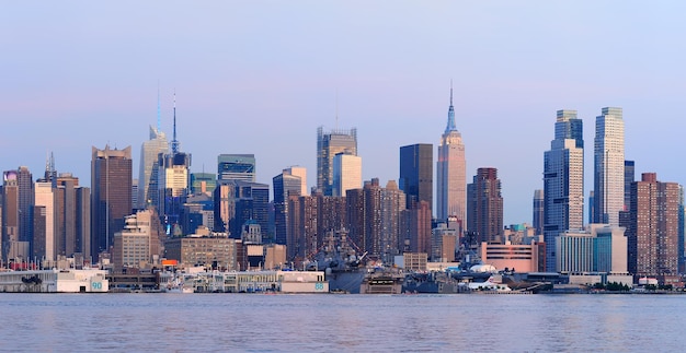 New York City Manhattan sunset panorama with historical skyscrapers over Hudson River viewed from New Jersey Weehawken waterfront at dusk with tranquil blue tone.