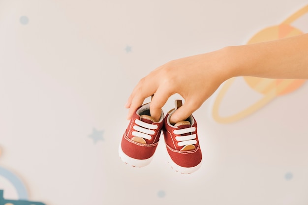 Free photo newborn concept with fingers holding shoes