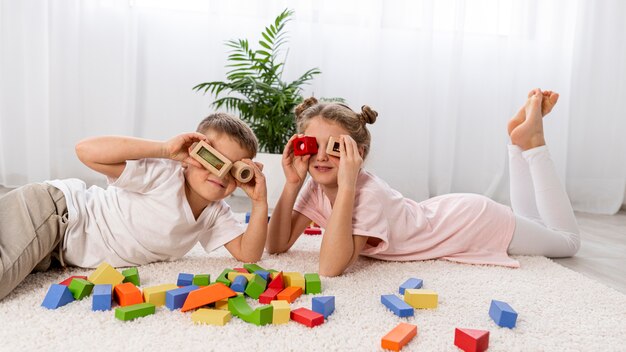 Free Photo non binary kids playing with a colorful game at home