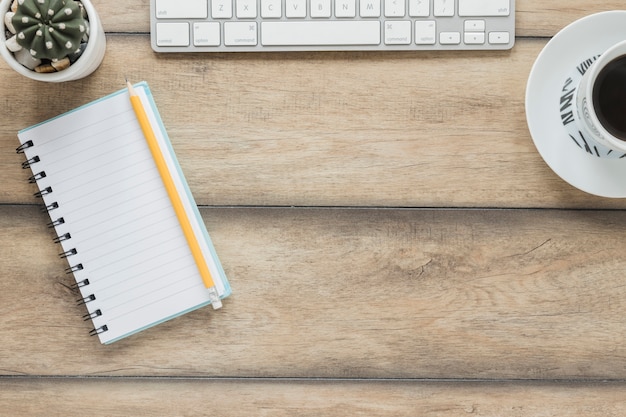 Free Photo notebook keyboard and coffee cup on wooden table