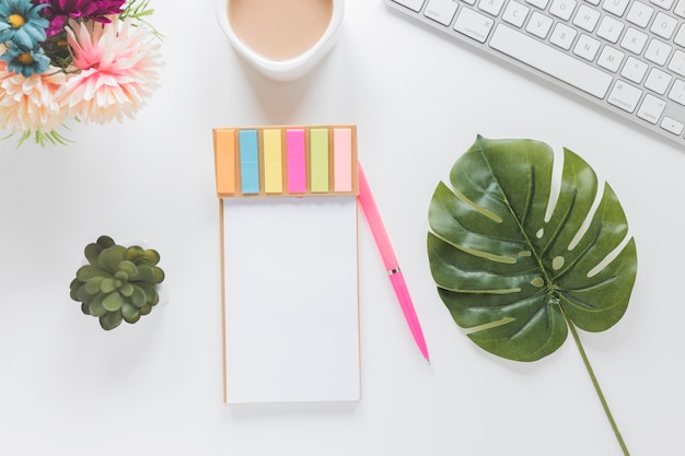 Free photo notebook with stickers near coffee cup, keyboard and plants