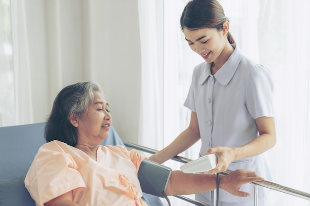 Free photo nurse measuring blood pressure of senior elderly woman in hospital bed patients - medical and healthcare senior concept