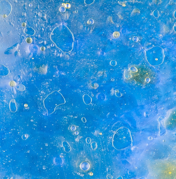 Free photo oil bubbles floating on blue water surface