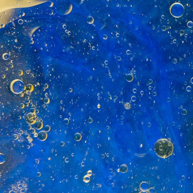 Free photo oil bubbles floating on blue watercolor background