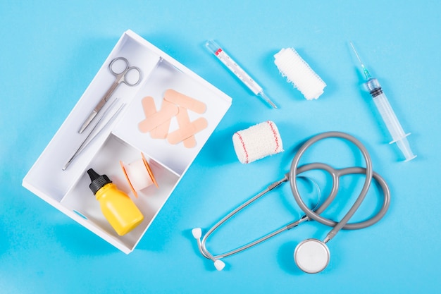 Free photo an open first aid kit with medical equipments on blue background