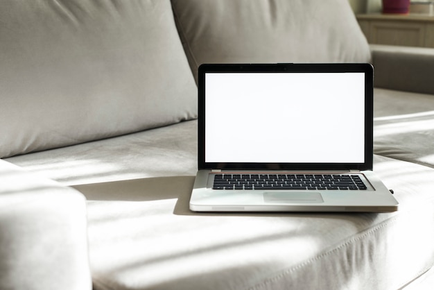 Free Photo an open laptop with white display screen on gray sofa