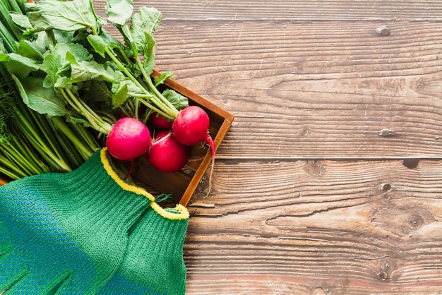 Free photo an organic turnip and green gardening gloves in wooden tray over the wooden desk