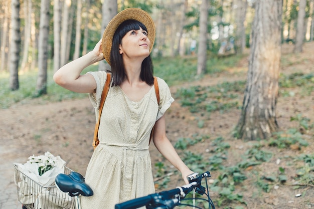 Foto gratuita ritratto all'aperto di giovane castana attraente in un cappello su una bicicletta.