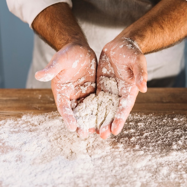 Foto gratuita una vista dall'alto della mano del fornaio con farina di grano