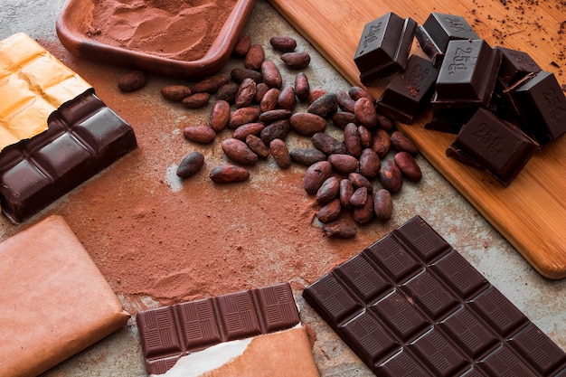 Foto gratuita vista dall'alto di tavolette di cioccolato con polvere di cacao e fagioli crudi