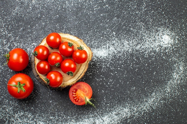 Free Photo overhead view of fresh tomatoes with stems on wooden board on the right side on white black background