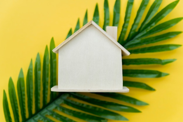 Free photo an overhead view of wooden house over the green leaves against yellow background