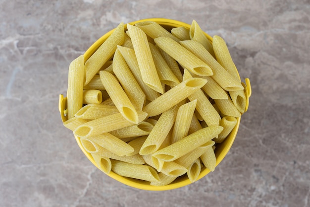 Free photo pasta in yellow bucket , on the marble surface.