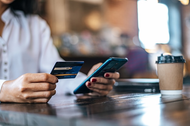 Free Photo pay for goods by credit card through a smartphone in a coffee shop.