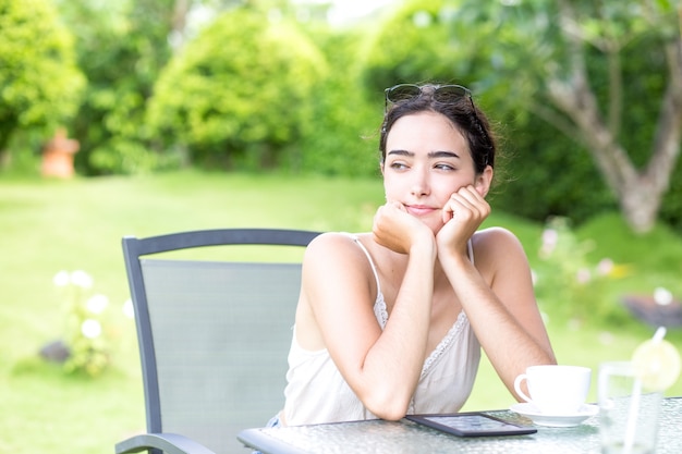 Free photo pensive young woman sitting in outdoor cafe