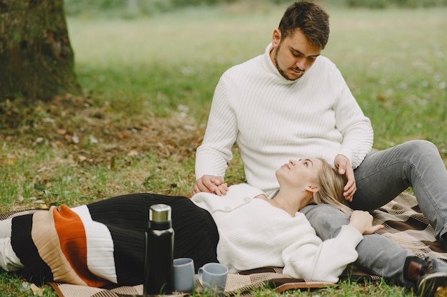 Foto gratuita persone in un parco. donna in un cappotto marrone. uomo con un maglione bianco. coppia in un picnic.