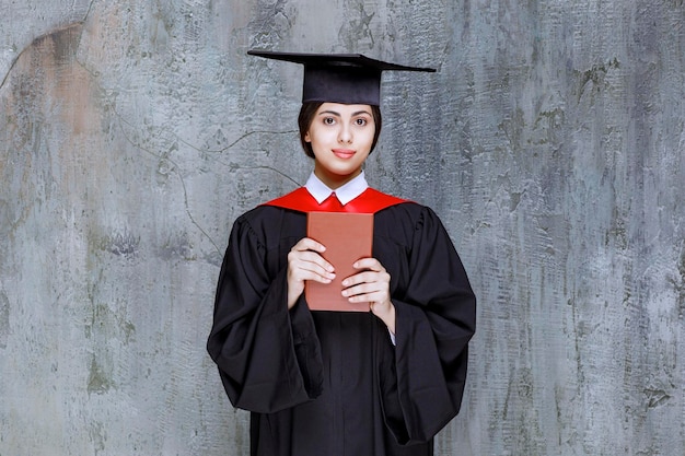 Free photo photo of smart graduate student showing her book over wall. high quality photo