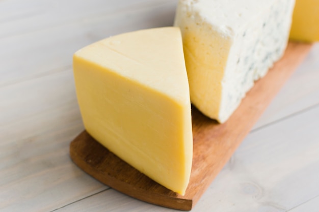 Free photo a piece of cheese on chopping board over the wooden table