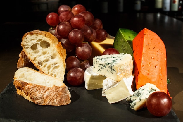 Free photo pieces of cheese and bread on black dish