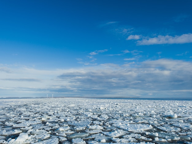 Pieces of ice in the frozen lake under the bright sky in winter