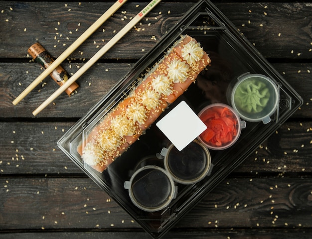 Free Photo plastic box of shushi rolls for delivery with salmon, sauces, wasabi, ginger