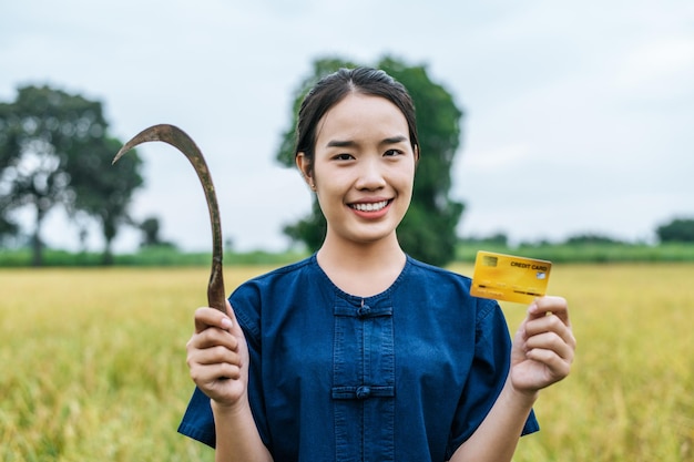 Free photo portrait of asian young farmer woman showing credit card on rice field