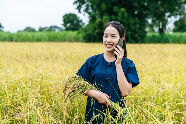 Free photo portrait beautiful asian young woman farmer use smartphone in organic rice field and smile with happiness