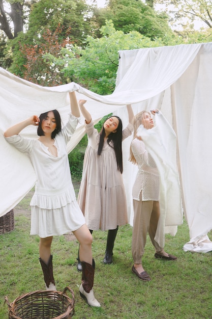 Free photo portrait of beautiful women at garden, standing and holding white cloth in white dress during daytime.