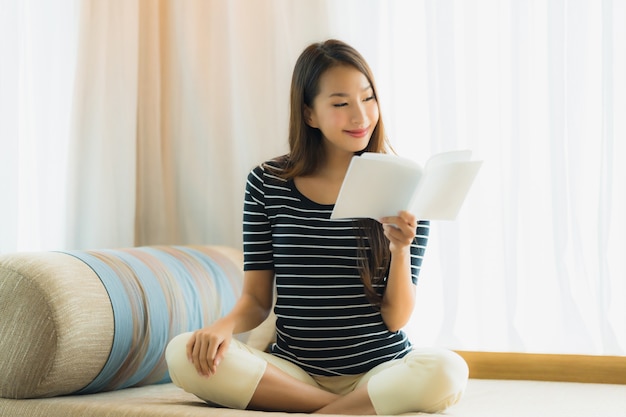 Free photo portrait beautiful young asian woman reading book in on sofa in living room area