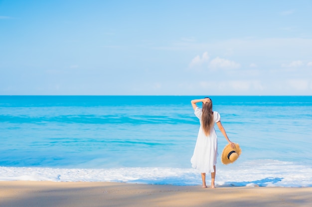 Free photo portrait of beautiful young asian woman relaxing around beach with white clouds on blue sky in travel vacation