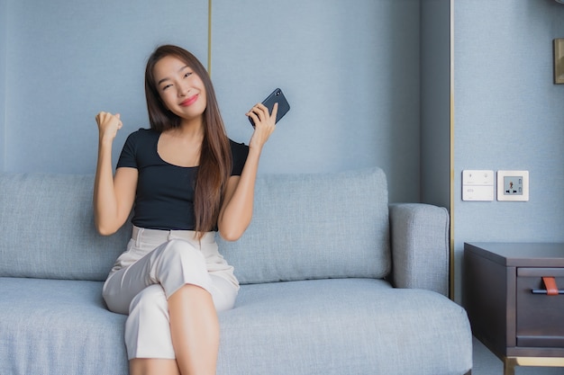 Free photo portrait beautiful young asian woman use smart mobile phone on sofa in living room area