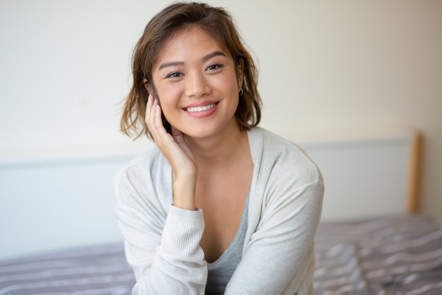 Free photo portrait of cheerful young woman sitting on bed