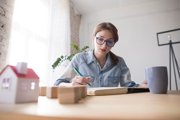 Portrait of a female architect writing on book at workplace