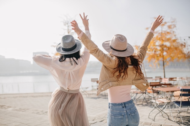 Free photo portrait from back of two excited ladies expressing positive emotions enjoying river views