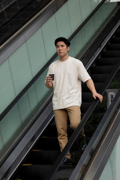 Free photo portrait of handsome asian man having coffee outdoors in the city