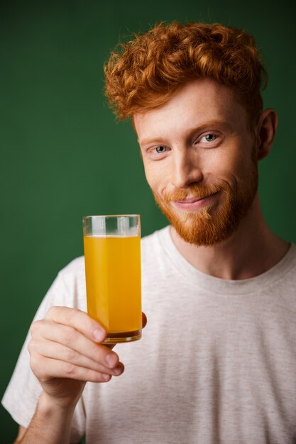 Portrait of handsome smiling bearded man holding glass of orange juice