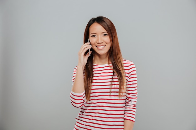 Free photo portrait of a smiling asian girl talking on mobile phone