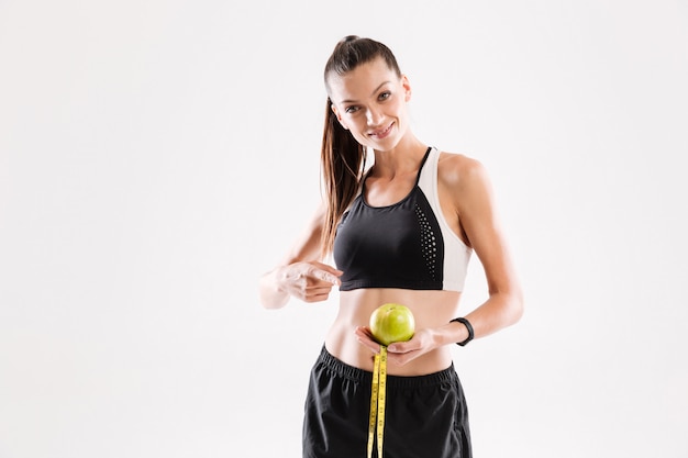 Free Photo portrait of a smiling young fitness woman holding green apple