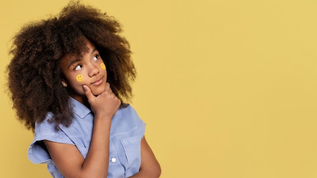 Free Photo portrait of young adorable girl posing with emoji stickers on her face