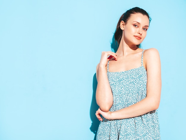 Free photo portrait of young beautiful smiling female in trendy summer blue dress sexy carefree woman posing near blue wall in studio positive model having fun and going crazy cheerful and happy