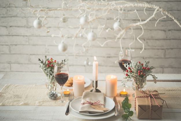 Free photo present, plates, cutlery, candles and decorations arranged on table for christmas dinner