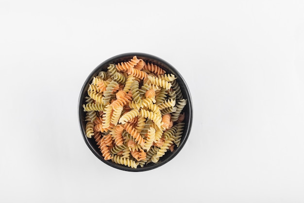 Free photo raw colorful fusilli pasta in dark bowl.